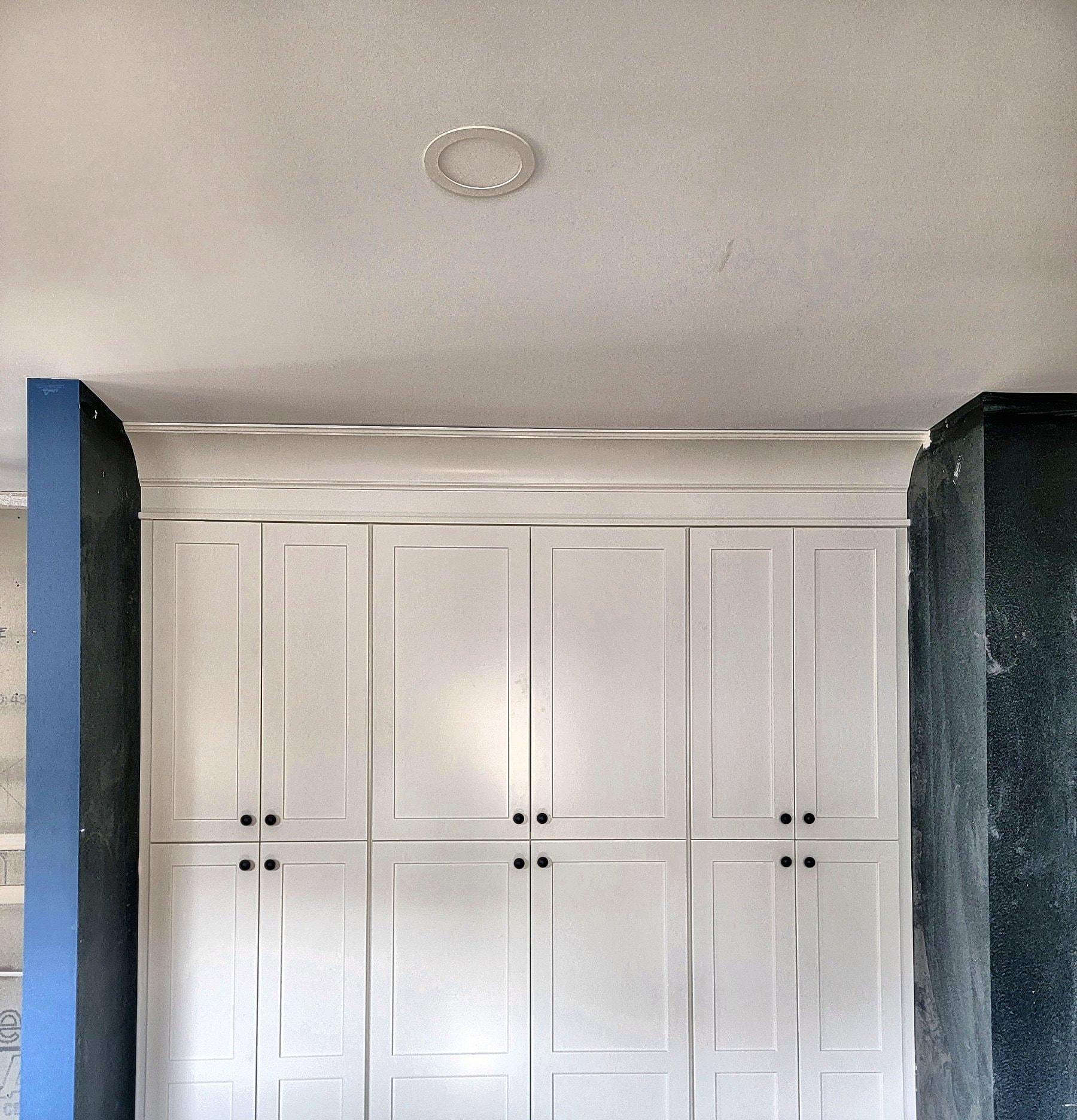 A wall of white floor-to-ceiling pantry cabinets. The bottom of the frame is cropped.