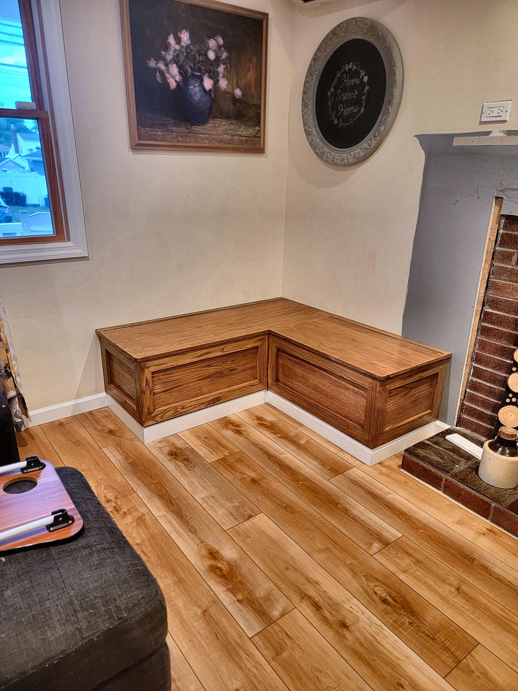 An L-shaped stained storage bench with hinged lids and the cushions off.